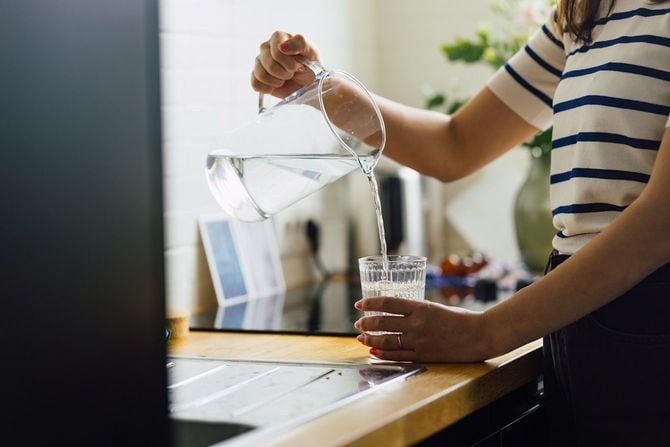 キッチンでコップに水を注ぐ女性