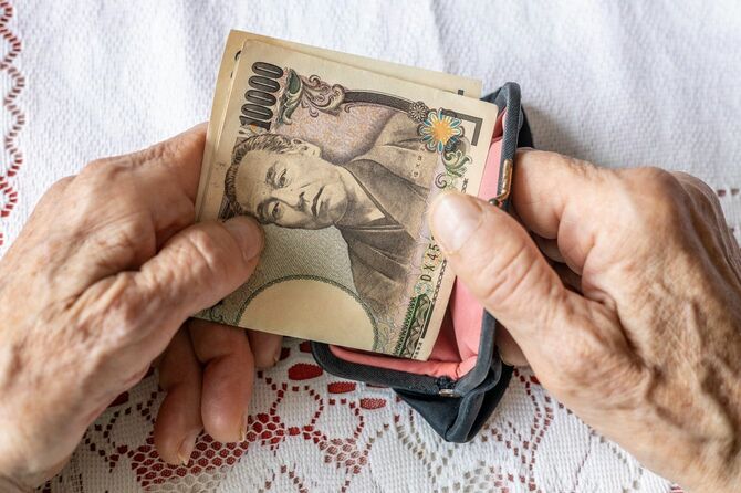 財布から1万円札を取り出す高齢女性の手