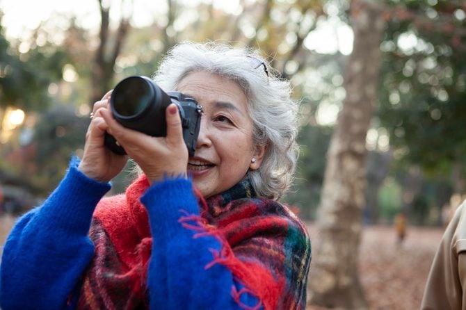 自然の中でデジタルカメラ撮影を楽しむシニア女性