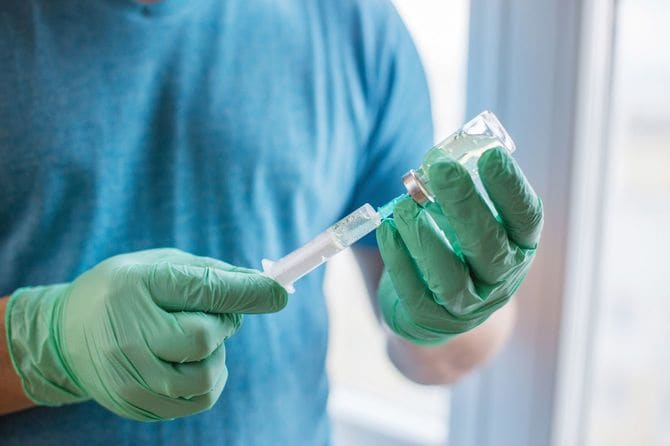 注射器をワクチンで満たす医師の手