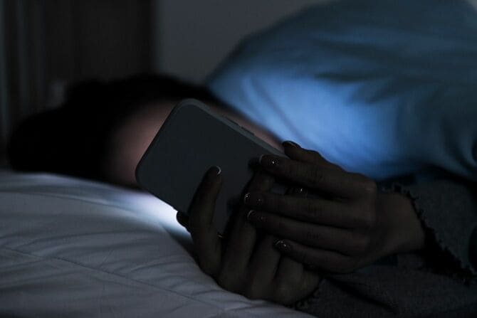夜中にベッドでスマートフォンを見る人