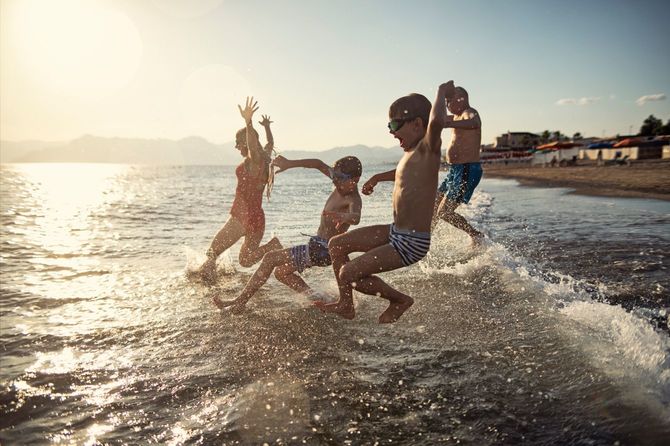 孫と一緒に海に走ったり飛び跳ねたりする老人