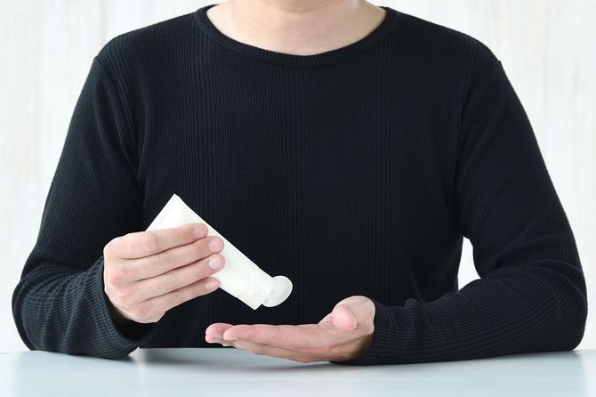 クリームを手に出す男性のイメージ