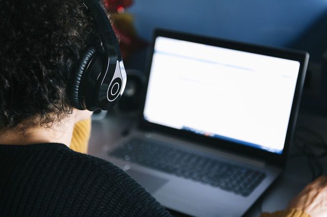 ラップトップを使用するヘッドホンをつけた女性