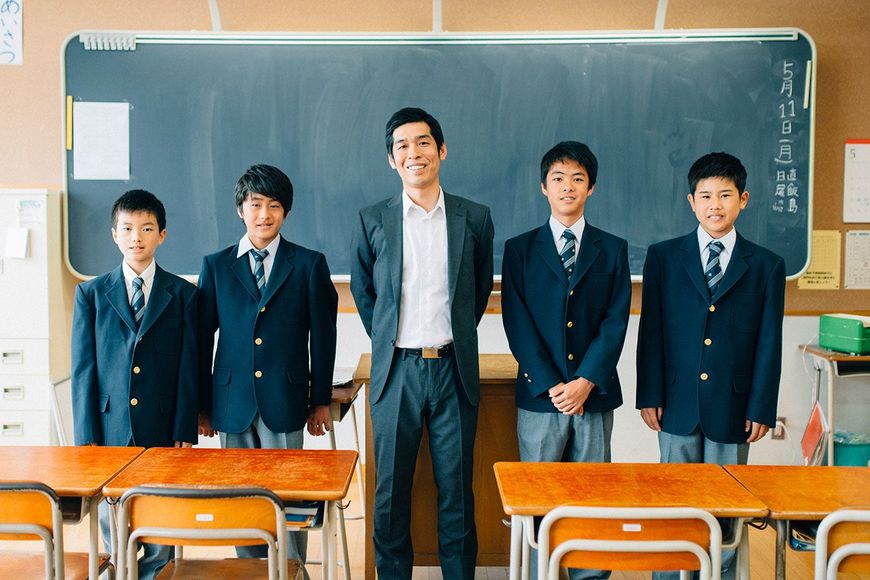 教室で先生を真ん中にして並ぶ生徒たち