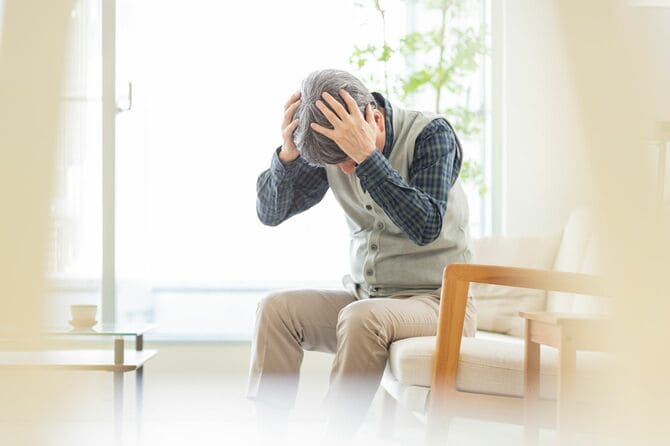 頭を抱えるシニア男性
