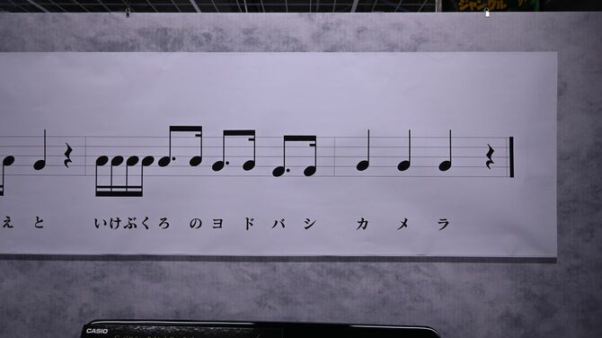 ヨドバシ池袋内にはテーマソングの譜面がかざられている。語呂あわせの16分音符が強硬だ