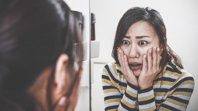 鏡を見てショックを受ける女性