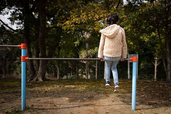 鉄棒の上に座っている子供