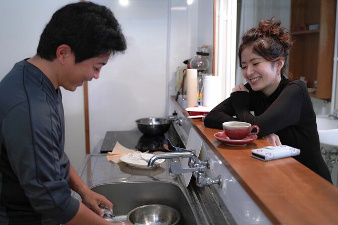 洗い物をする男性とカウンターキッチン越しに笑顔で会話している女性