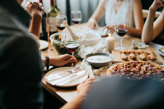 テーブルを挟んで食事とワインを楽しむ、楽しげな若いアジア人男女のグループ