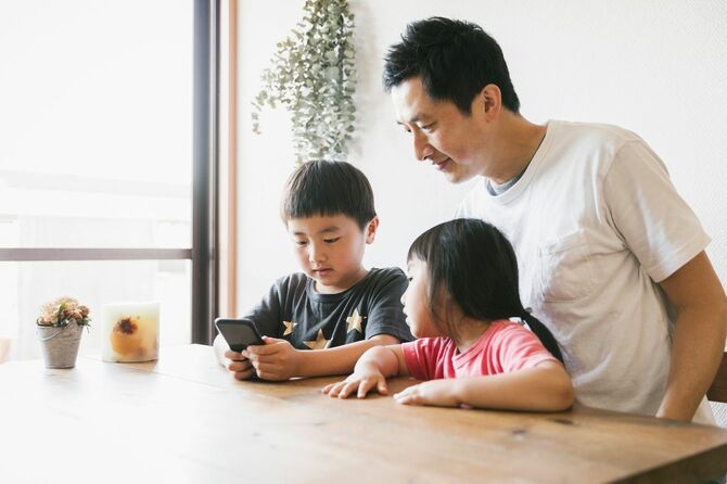 自宅で一緒にスマートフォンを使用する家族