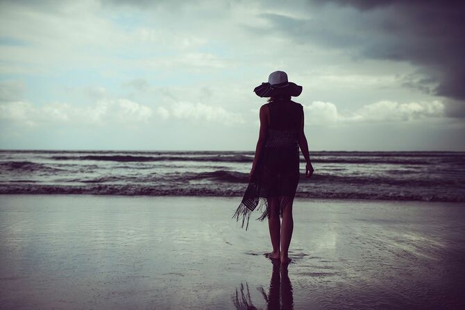 嵐の海に向かって行くと帽子とサンドレス女性