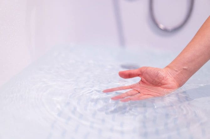 お風呂のお湯に手を入れて温度を確認する様子