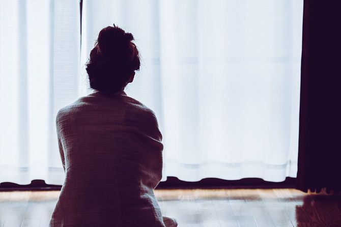 窓際に座っている孤独な女性の後ろ姿