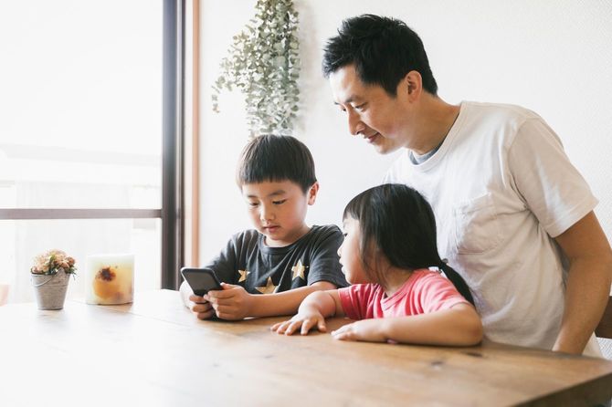 自宅で一緒にスマートフォンを使用する家族