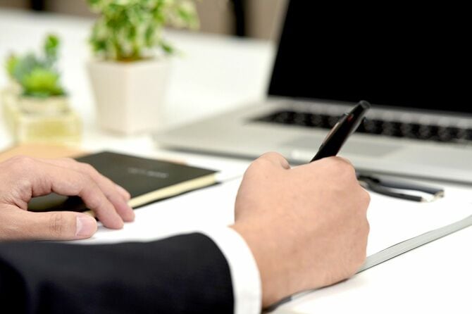 書類を書くスーツ姿のビジネスマンの手