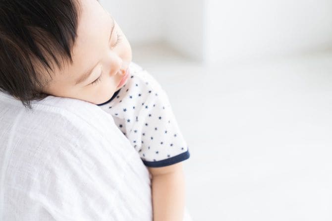 お母さんの肩にもたれて眠る赤ちゃん