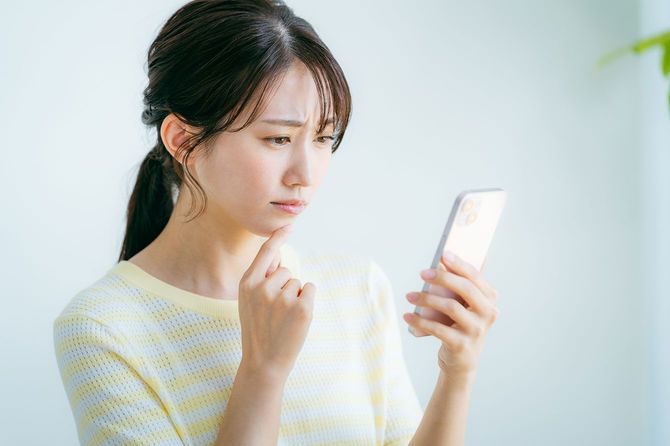 顔をしかめてスマホを見ている女性