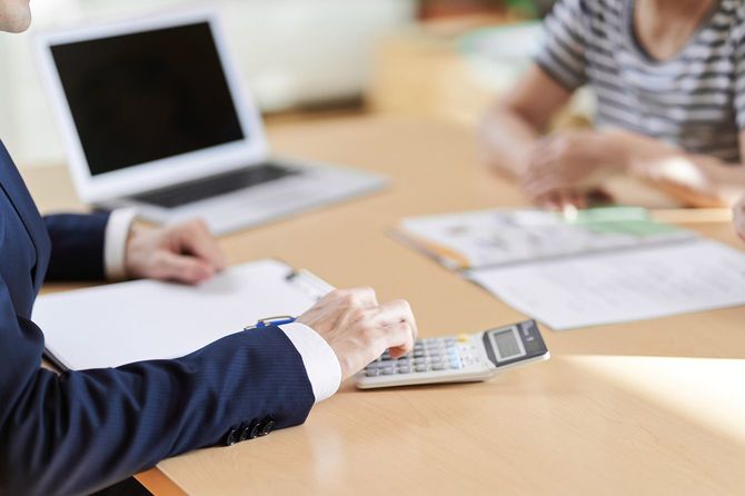 電卓で計算しながら客に説明をする営業マン