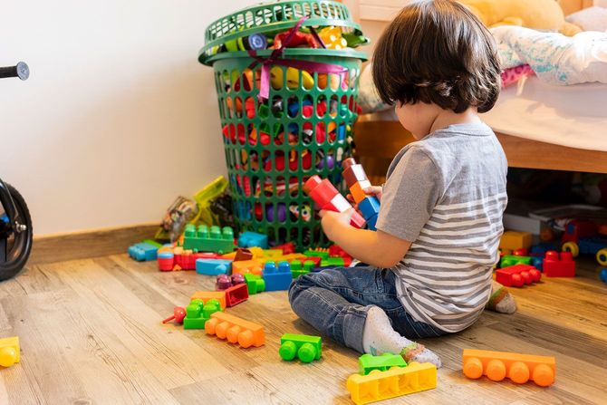 床に散らばったブロックで遊ぶ子ども