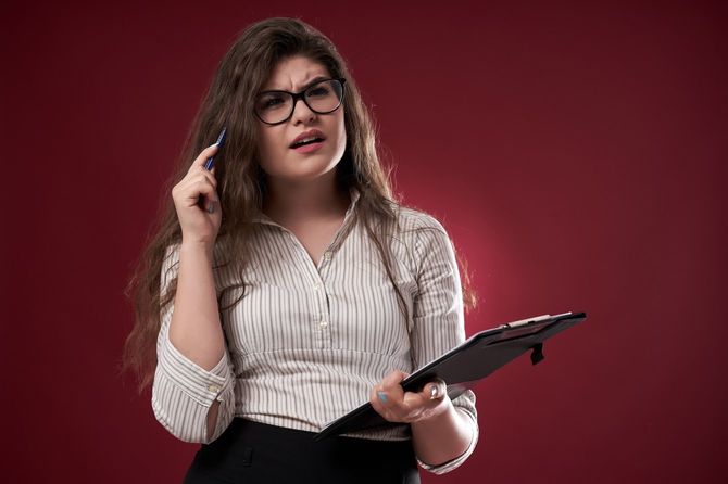 クリップボードを持って悩むビジネスウーマン