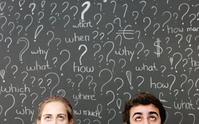 黒板いっぱいの疑問符の前で考える男女