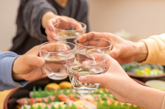 寿司が並ぶ食卓で、日本酒で乾杯する親族