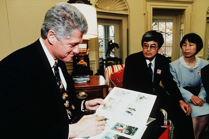 銃規制の署名簿をクリントン大統領に提出した服部さん夫妻と、剛丈さんの写真を見入るクリントン大統領＝1993年11月16日、アメリカ・ワシントン