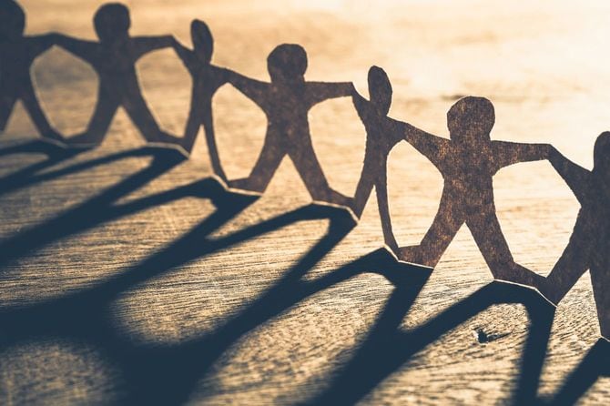 手をつないで輪をつくる紙の人形と、長く伸びる影