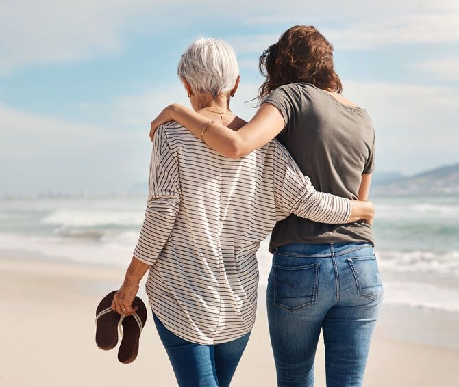 高齢の母親とビーチで散歩する若い女性