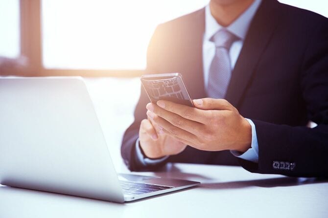 スマホとノートパソコンを使用するビジネスマン
