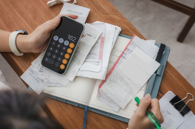 スマートフォンの電卓を使用し、レシートの確認をしている人の手元