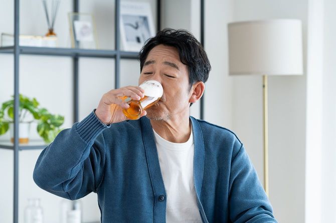 自宅でビールを飲む中年男性