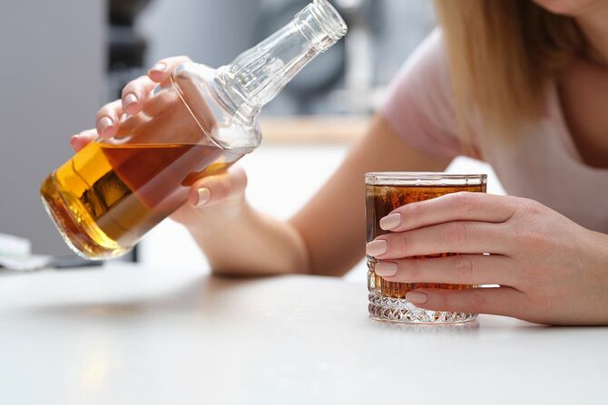 女性がアルコールコニャックやウイスキーを一人で飲む
