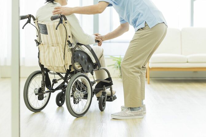 車椅子の女性に寄り添う介護施設の職員