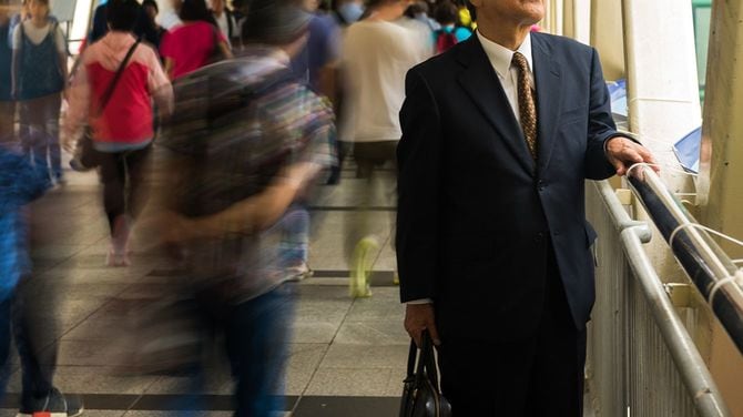 群衆の中から目立つアジア系の上級のビジネスマン