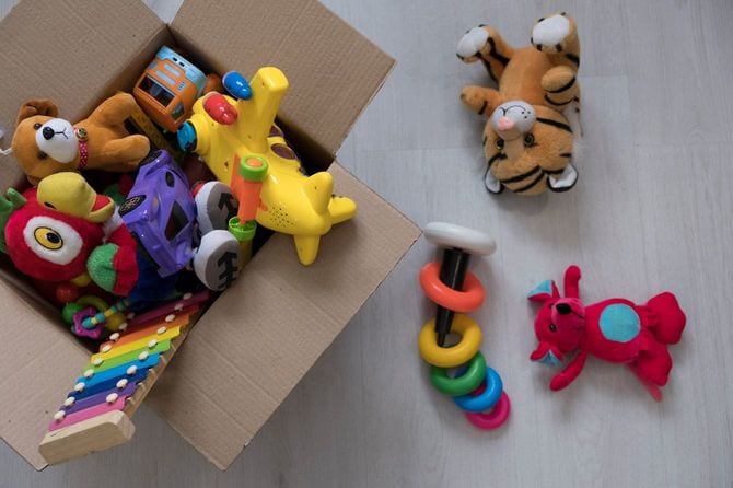 床に置かれたおもちゃ箱から玩具が零れ落ちている