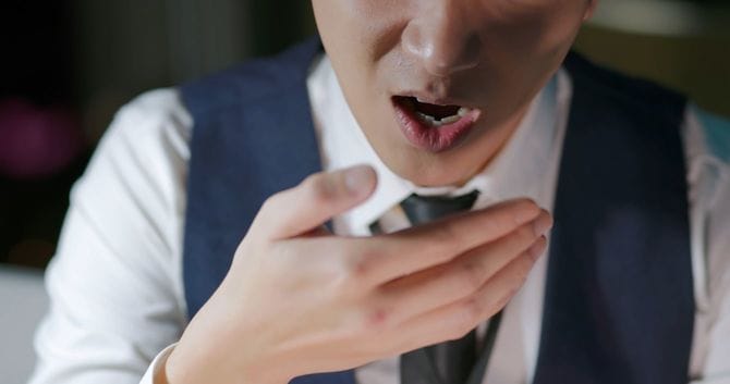 手のひらに息を吹きかけているビジネスマン