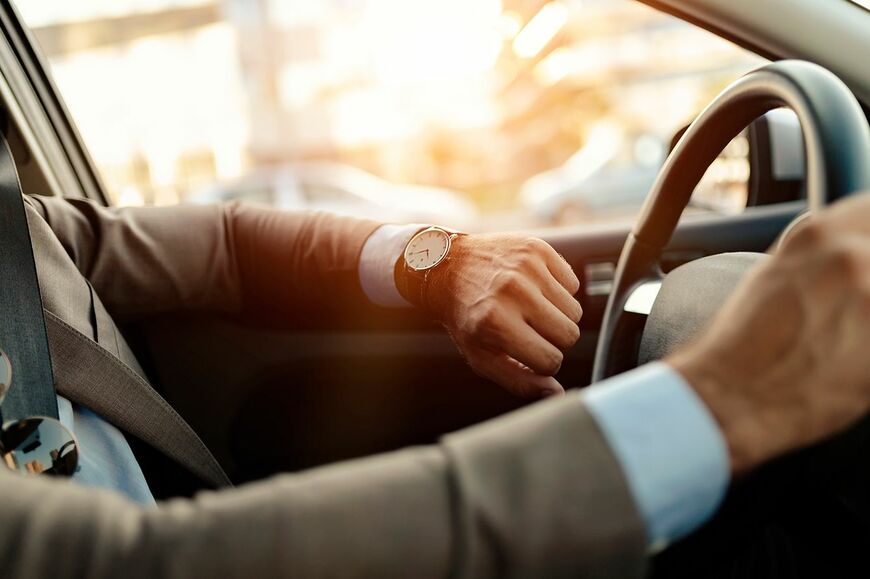 ビジネスマンは彼の車の中で時計を見ている