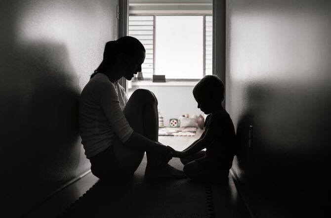 暗い廊下に座り込む母と息子