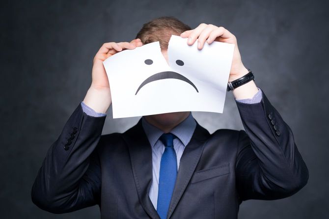 顔の描かれた紙を顔の前で破る男性