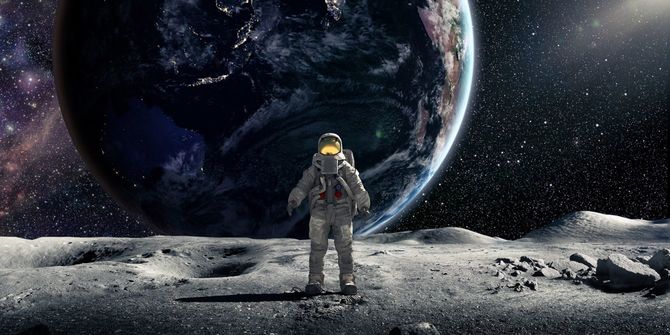 地球を背景にカメラに向かって月に立つ宇宙飛行士