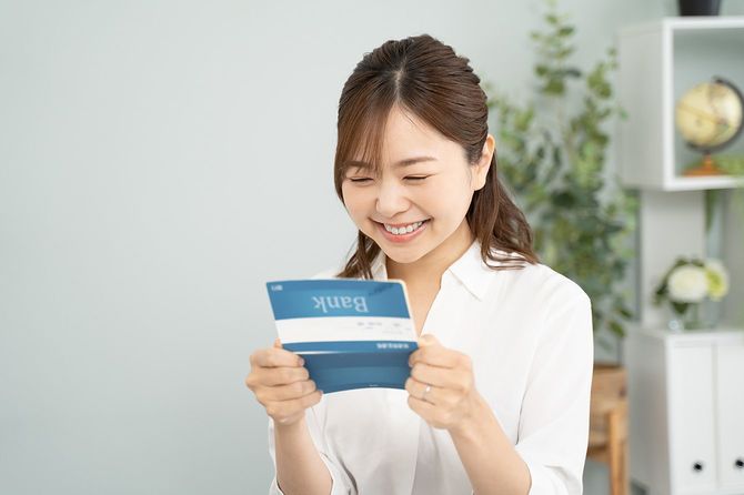 通帳を見てほほ笑む女性