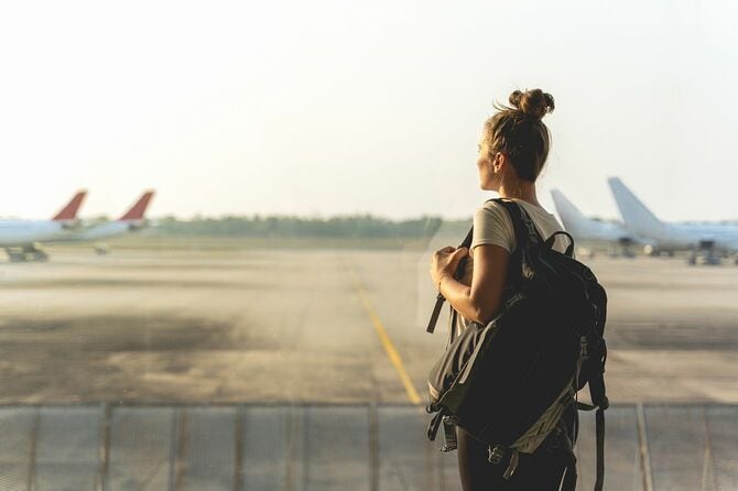 飛行機を見ている空港の出発ホールに立っている女性