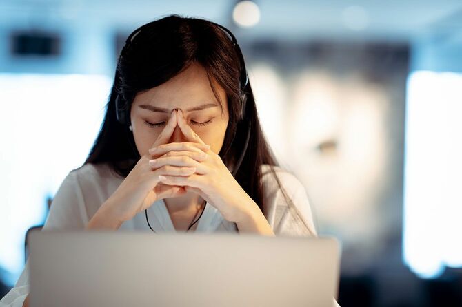 オフィスのパソコンの前で疲れたようにうつむく女性