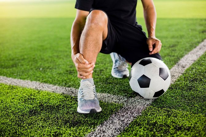 違和感のあるすねに手を当てている選手