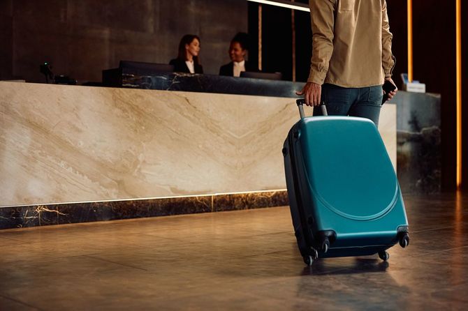 ホテルの廊下で旅行バッグを持った男性のクローズアップ