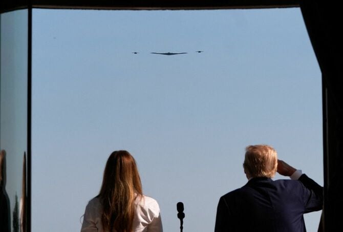 2025年7月4日、ワシントンD.C.で行われた独立記念日の祝賀行事で、ホワイトハウスのブルールームのバルコニーから、ステルス爆撃機B-2スピリットによる軍事飛行を観覧するドナルド・トランプ米大統領とメラニア夫人