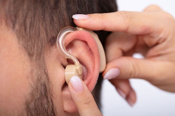 患者の耳に補聴器を装着する医師の手